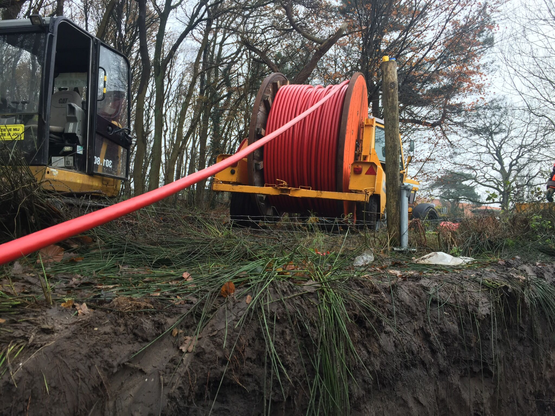 Haspelwagen met rode elektriciteitskabel in een bosrijk tracé